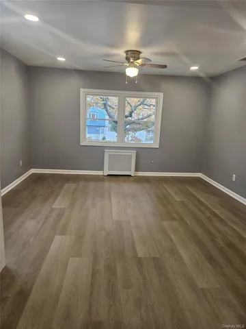 an empty room with wooden floor a ceiling fan and window