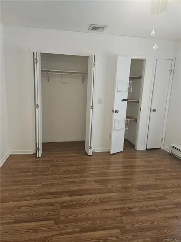 a view of an empty room with wooden floor and a bathroom