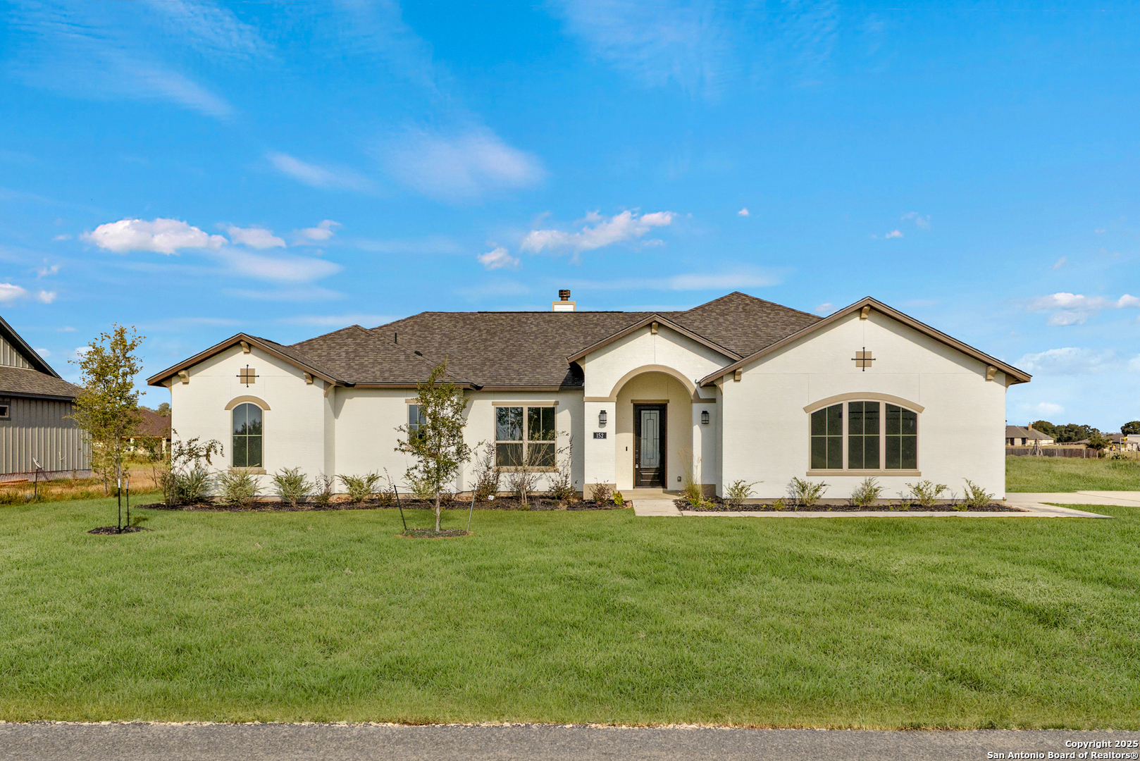 a front view of a house with a garden and trees