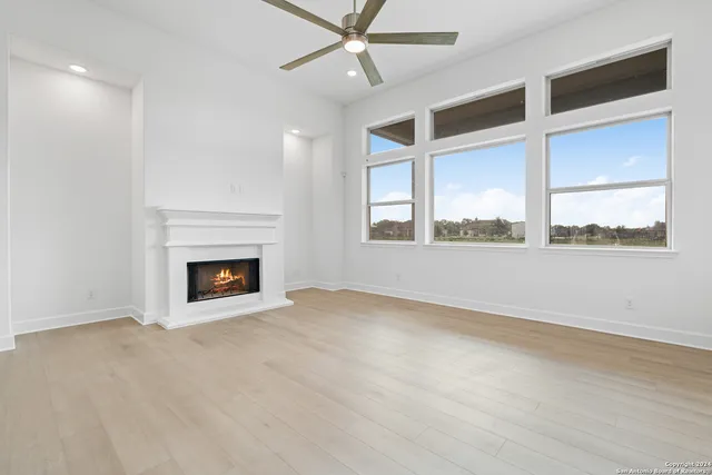 a kitchen with granite countertop a stove a sink and white cabinets with wooden floor