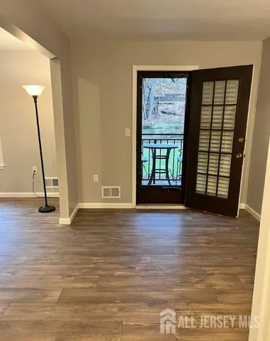 a view of an empty room with window and wooden floor
