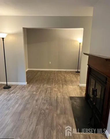 a view of an empty room with wooden floor and a fireplace