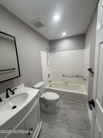 a bathroom with a tub sink toilet and a mirror