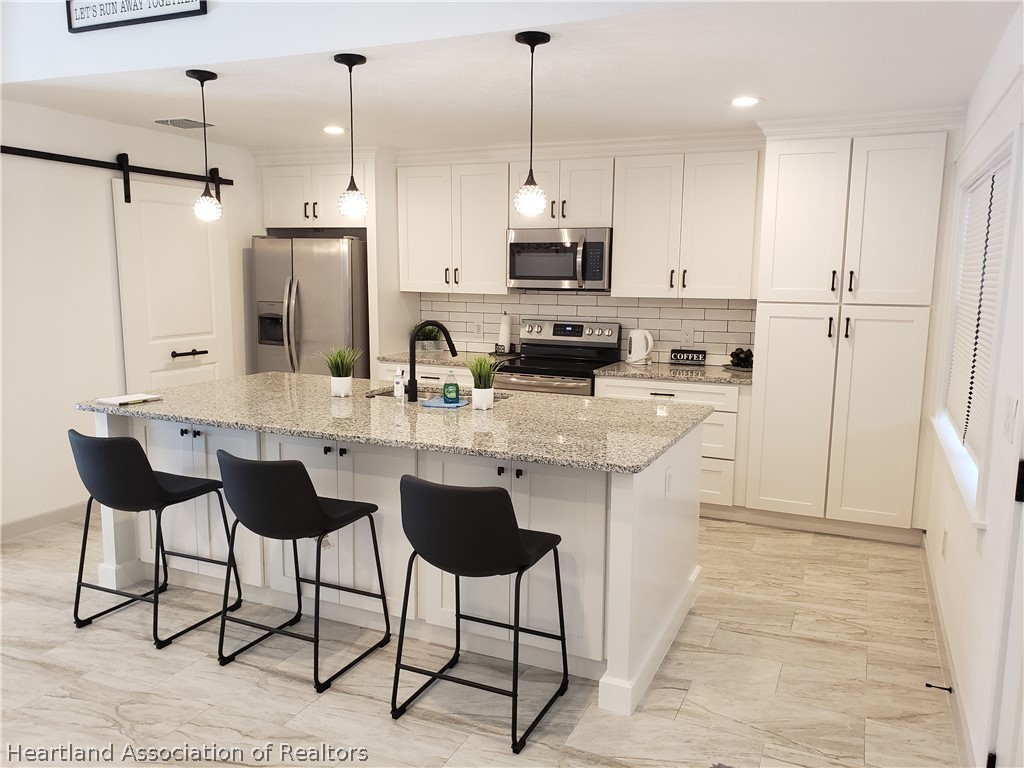 2247 West Longbottom Road Avon Park, FL 33825 - Photo 4 of 21 a kitchen with stainless steel appliances kitchen island granite countertop a sink a refrigerator and a stove