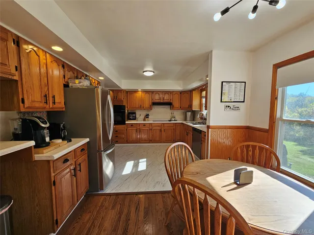 a kitchen with stainless steel appliances granite countertop a refrigerator a stove top oven a sink and dishwasher with wooden floor