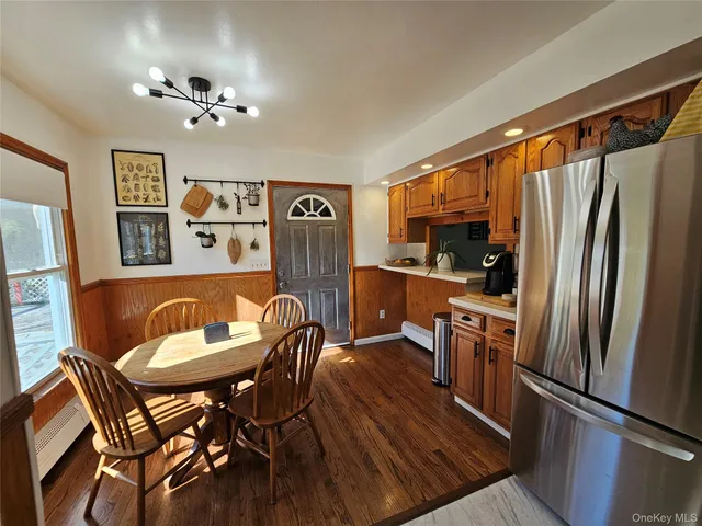 a kitchen with stainless steel appliances granite countertop a dining table chairs refrigerator and sink