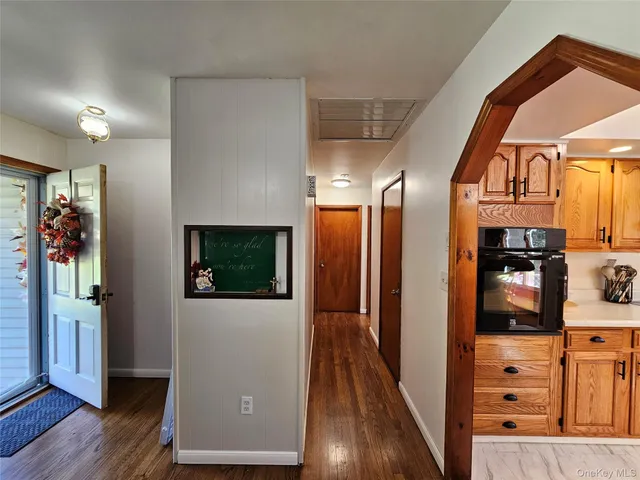 a view of a hallway with wooden floor and living room