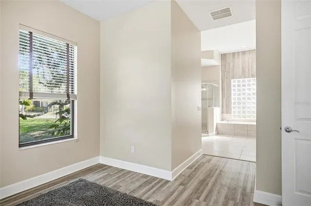 a view of an empty room with wooden floor and a window