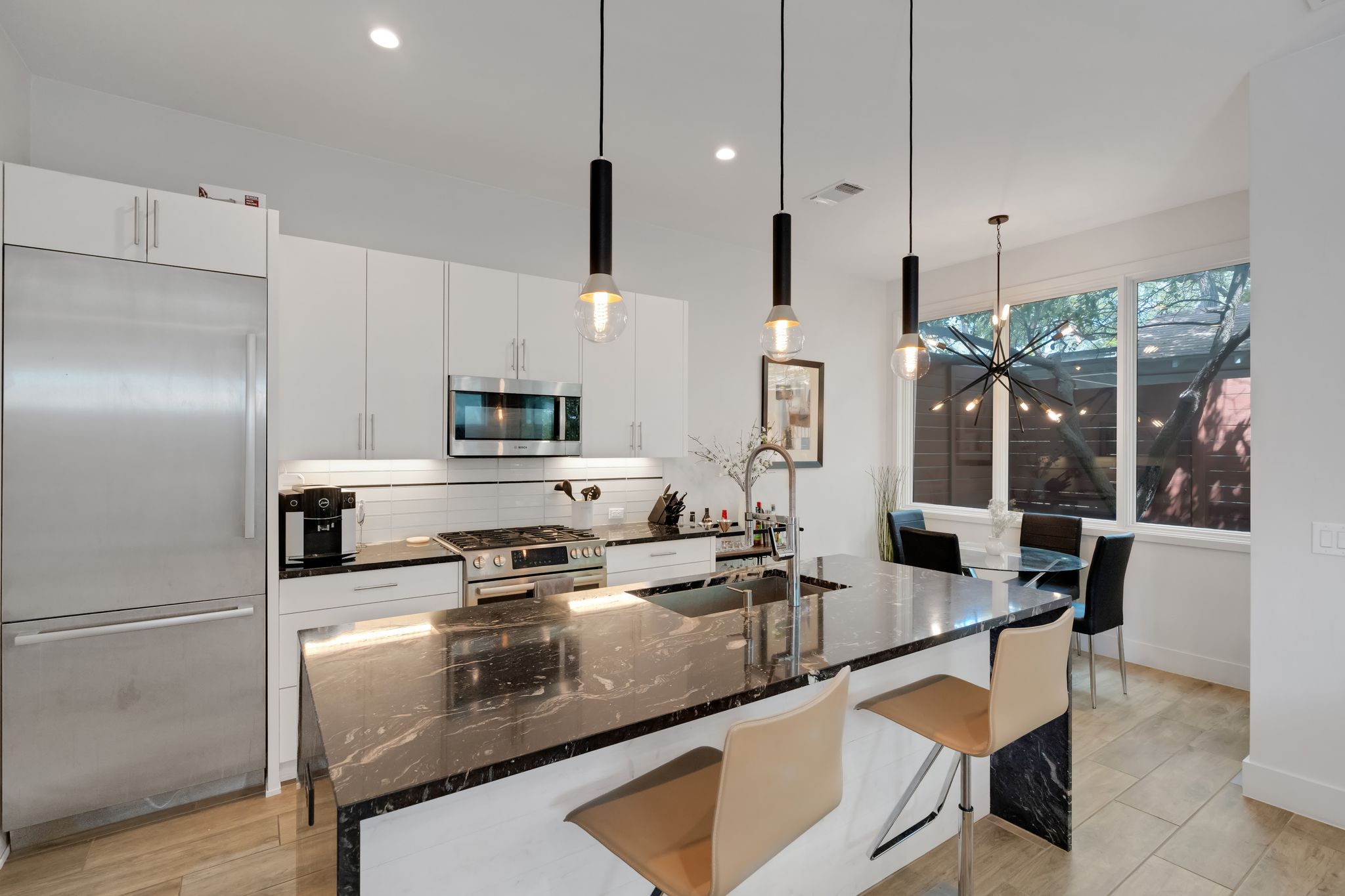 809 Bouldin Avenue Austin, TX 78704 - Photo 28 of 39 Kitchen featuring stainless steel appliances, suspended lighting, dark stone countertops, a kitchen bar, and a kitchen island with sink