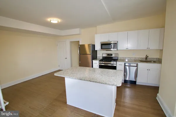 a kitchen with granite countertop a refrigerator a stove top oven a sink and dishwasher