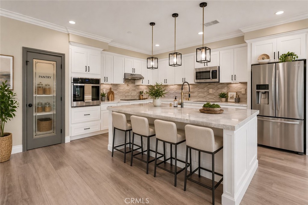 14388 Dove Canyon Drive Riverside, CA 92503 - Photo 5 of 38 a kitchen with stainless steel appliances kitchen island granite countertop a refrigerator a stove a microwave oven a sink with island and chairs with wooden floor
