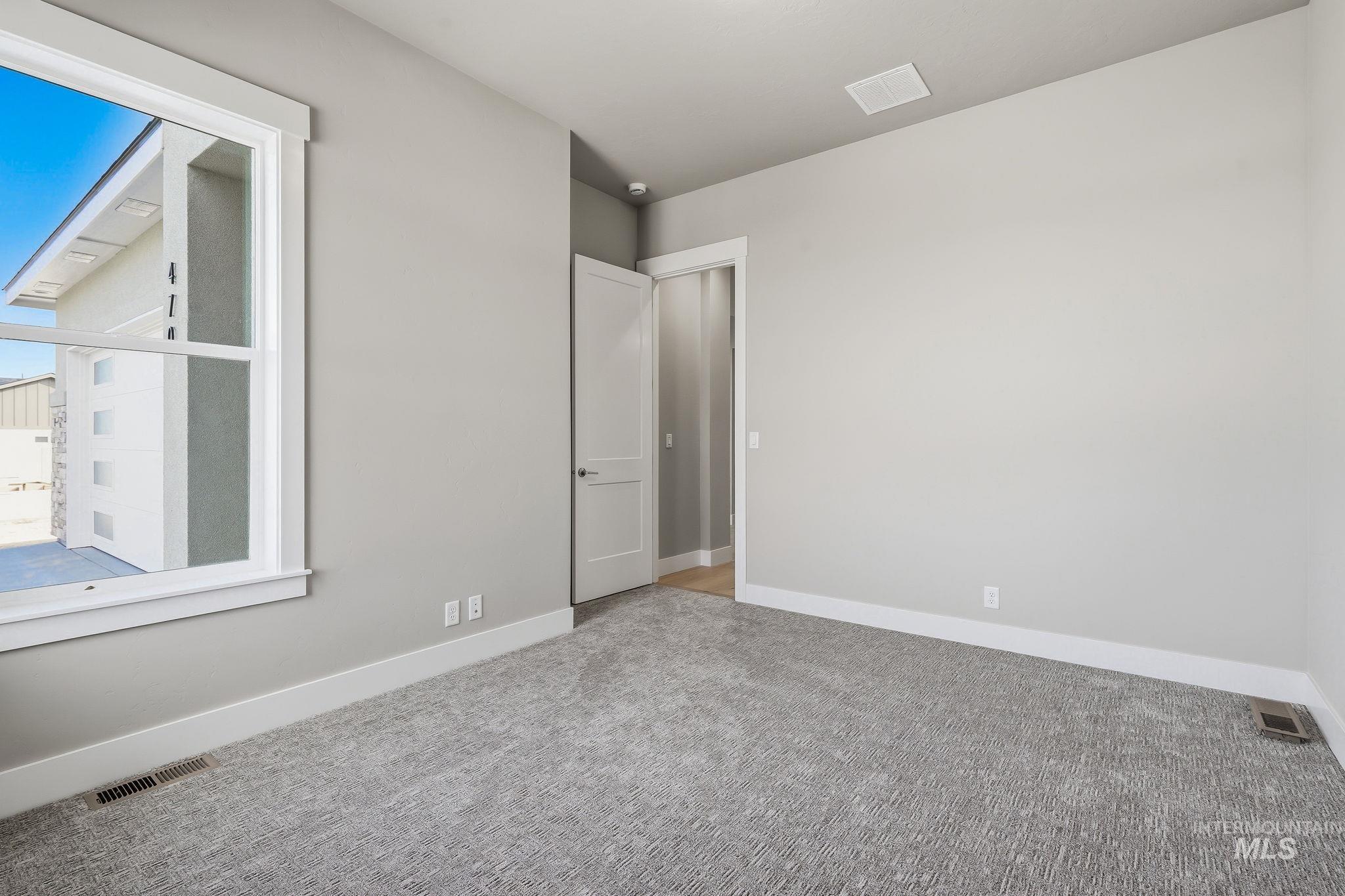 470 South Radiator Way Boise, ID 83716 - Photo 35 of 50 Bright interior room featuring a large double-hung window with white trim, light gray textured carpeting, and neutral wall paint