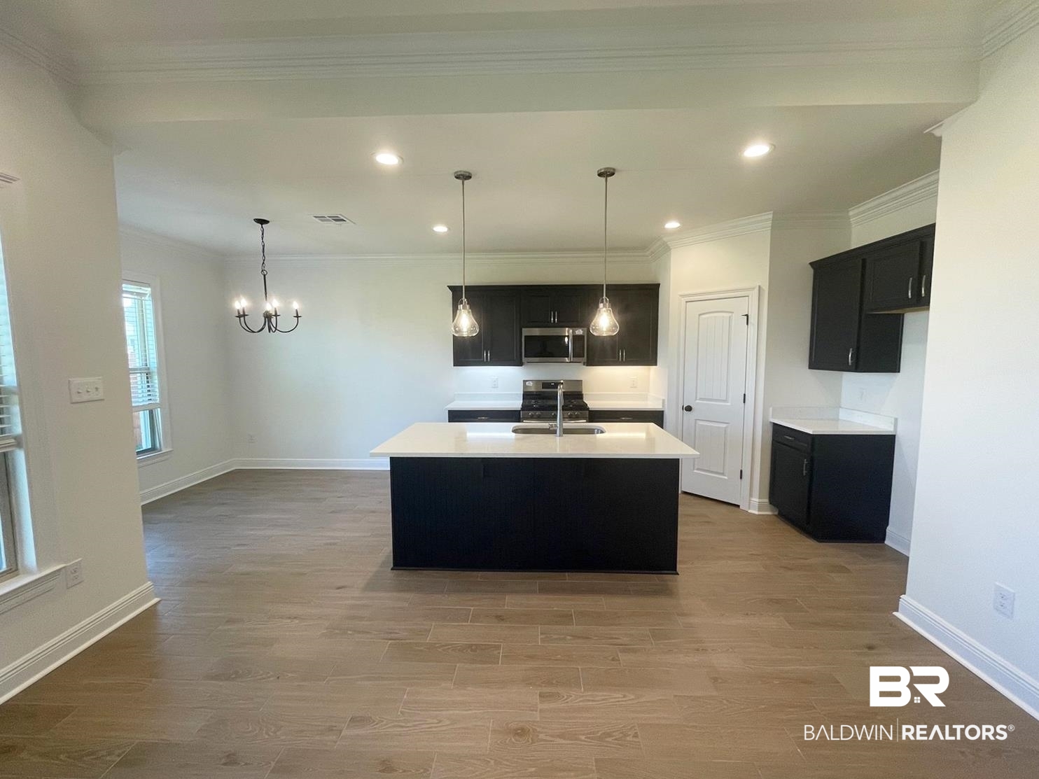 1565 Fenton Circle Foley, AL 36535 - Photo 2 of 15 Kitchen with pendant lighting, wood-type flooring, a kitchen island with sink, appliances with stainless steel finishes, and crown molding