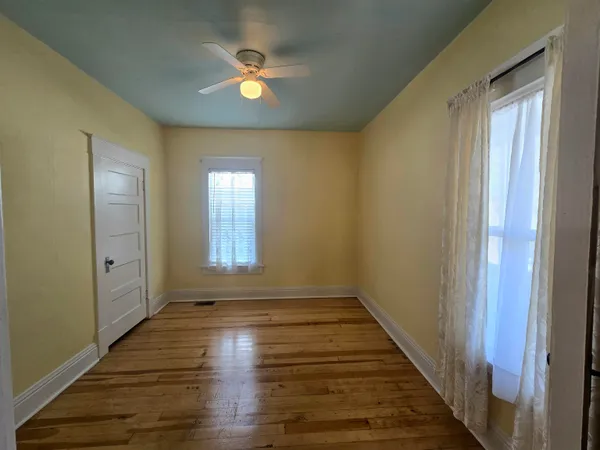 a view of an empty room with window and wooden floor