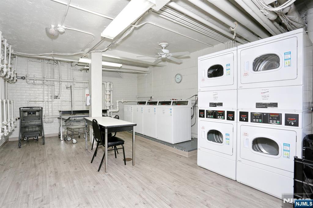 208 Anderson Street, Unit S4F Hackensack, NJ 07601 - Photo 18 of 20 a kitchen with a dining table chairs and white appliances with wooden floors