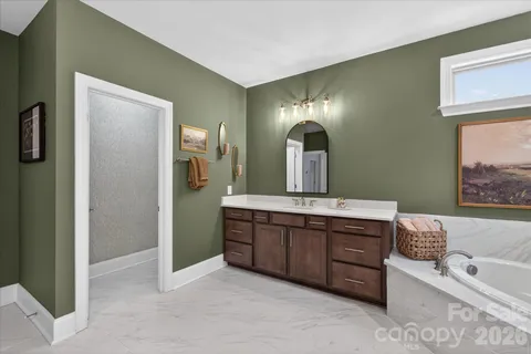 a spacious bathroom with a tub sink and mirror