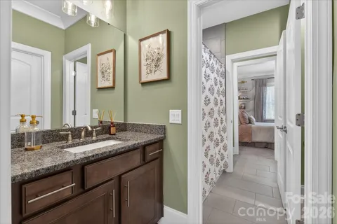 a en suite bathroom with a granite countertop sink a mirror and a shower