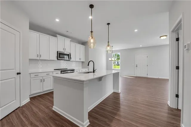 a large kitchen with stainless steel appliances sink a microwave and wooden floor