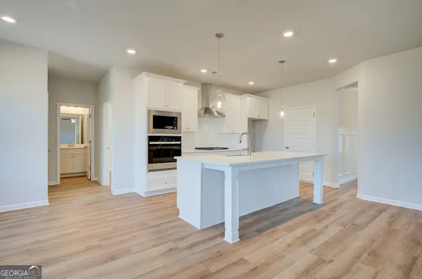 a large kitchen with a center island wooden floor stainless steel appliances and cabinets