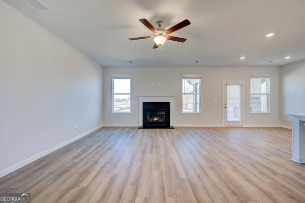 an empty room with wooden floor and a ceiling fan