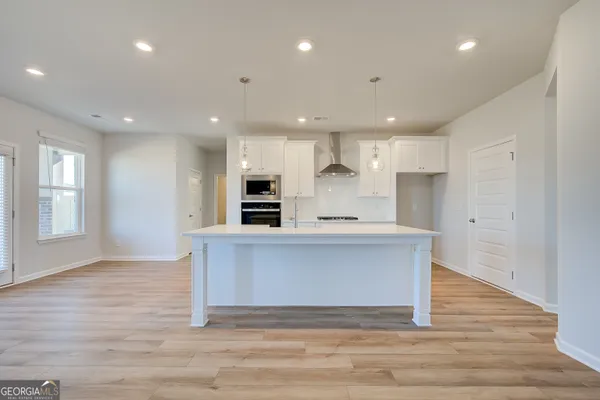 a large kitchen with stainless steel appliances granite countertop a large counter top a sink and a refrigerator
