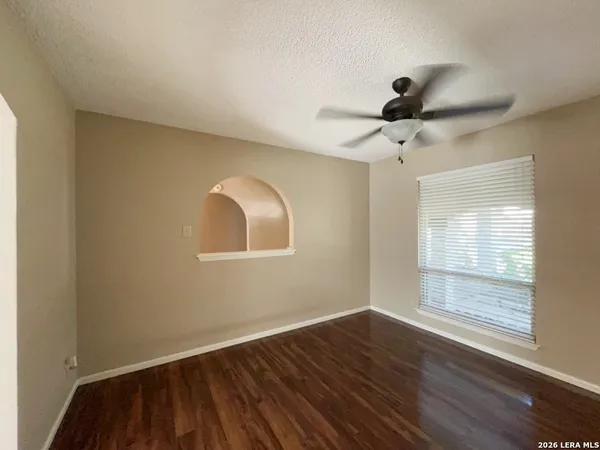 a view of empty room with wooden floor and fan