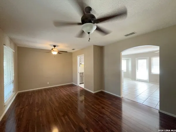 an empty room with wooden floor fan and windows