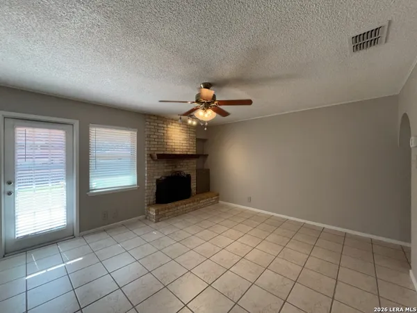 a view of an empty room with window and a fireplace