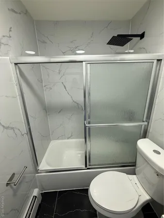 a white toilet sitting next to a shower