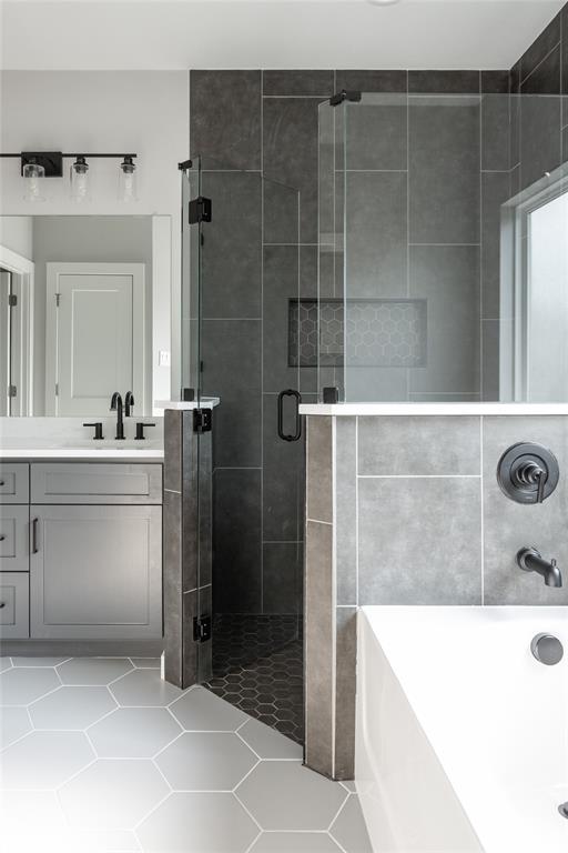1108 Claude Street Dallas, TX 75203 - Photo 15 of 17 Contemporary bathroom featuring a walk-in shower with dark gray tile, a recessed niche with hexagonal mosaic tile, and a glass enclosure with matte black hardware