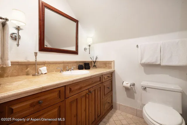 a bathroom with a granite countertop toilet sink and mirror