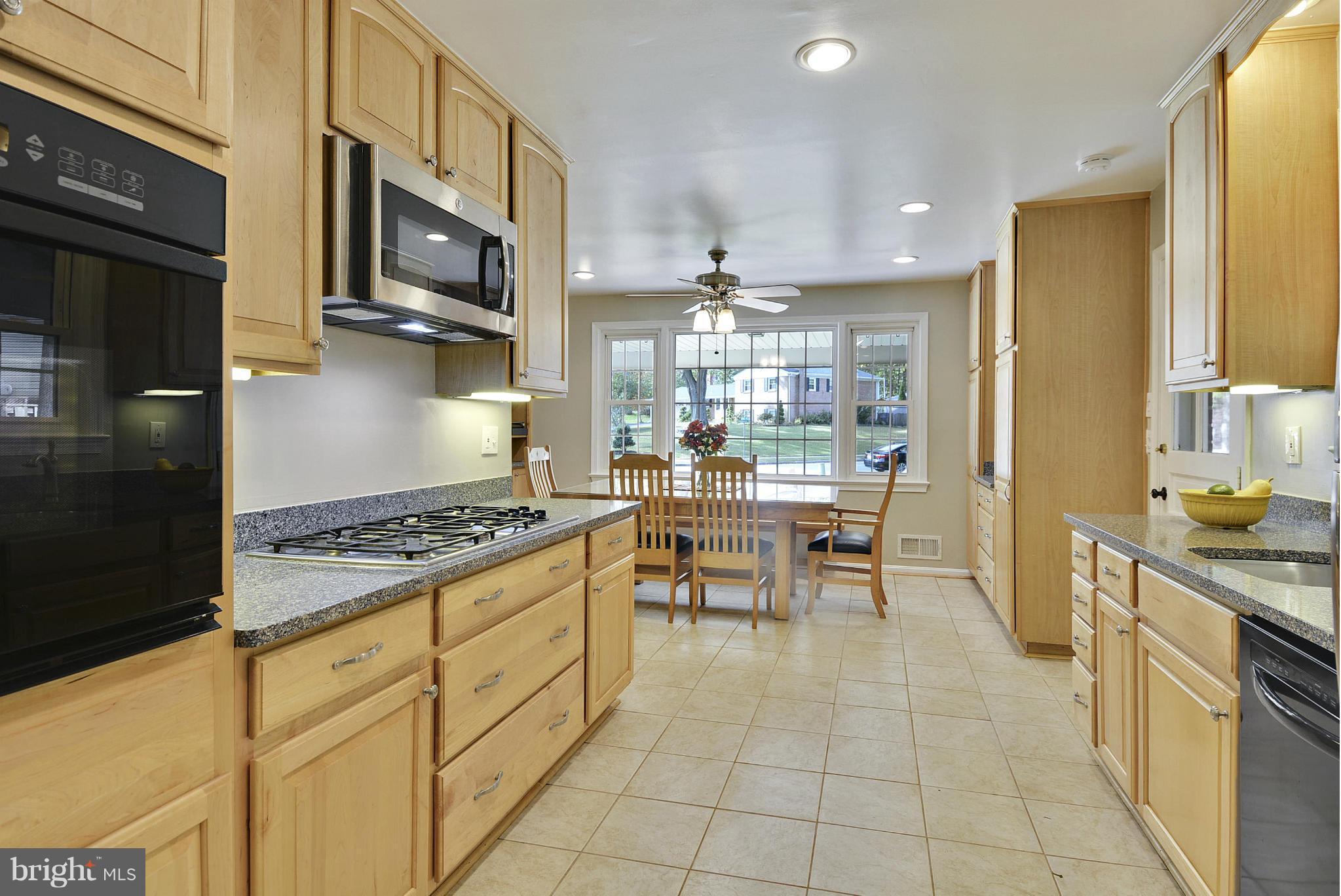 6731 Houndmaster Road Springfield, VA 22152 - Photo 4 of 30 a kitchen with stainless steel appliances granite countertop a stove top oven a sink dishwasher a dining table and chairs with wooden floor