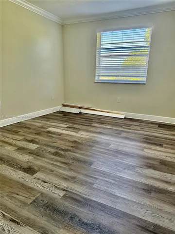 a view of a room with wooden floor and a window
