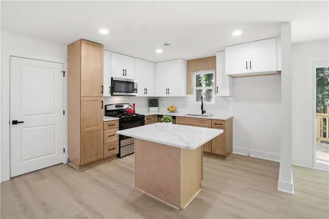 a kitchen with kitchen island a sink and a stove top oven with wooden floor