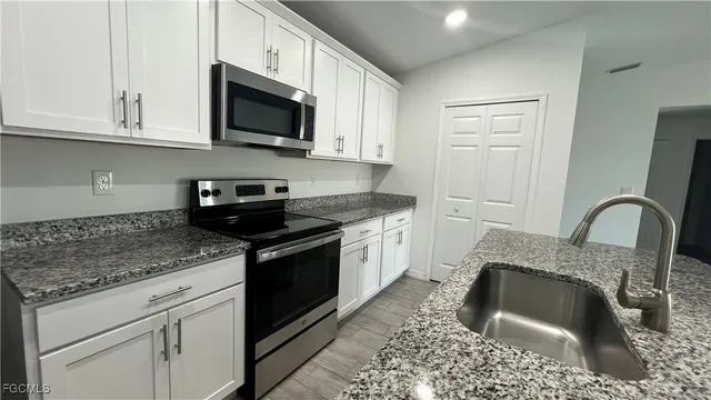a kitchen with granite countertop a sink a stove and cabinets