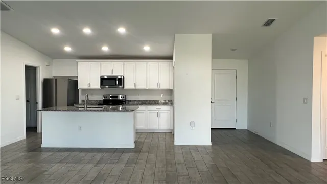 a kitchen with stainless steel appliances granite countertop a refrigerator a sink a stove a microwave and white cabinets