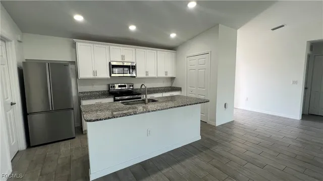 a kitchen with stainless steel appliances granite countertop a refrigerator and a stove top oven