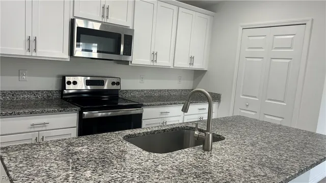 a kitchen with stainless steel appliances granite countertop a stove a microwave and a white cabinets