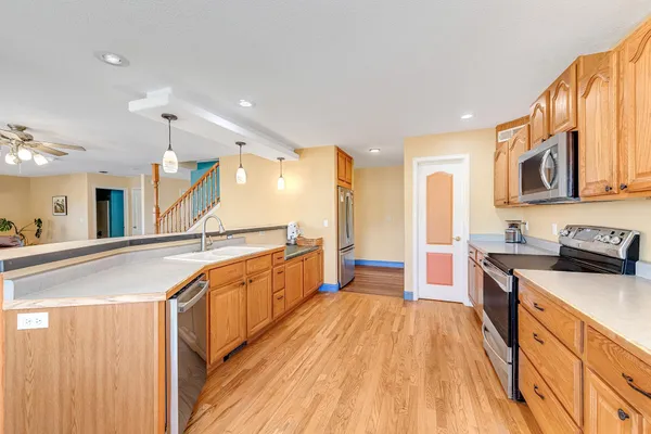 a large kitchen with stainless steel appliances granite countertop a lot of counter space and wooden floors
