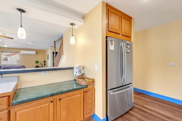 a kitchen with stainless steel appliances granite countertop a refrigerator a oven and white cabinets with wooden floors