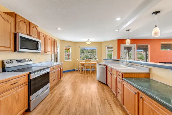 a kitchen with stainless steel appliances granite countertop wooden cabinets a stove top oven a sink and dishwasher a oven with wooden floor