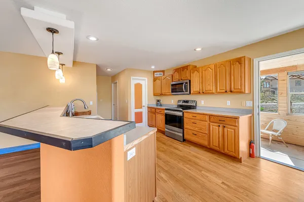 a kitchen with stainless steel appliances granite countertop a sink dishwasher stove refrigerator and cabinets with wooden floor