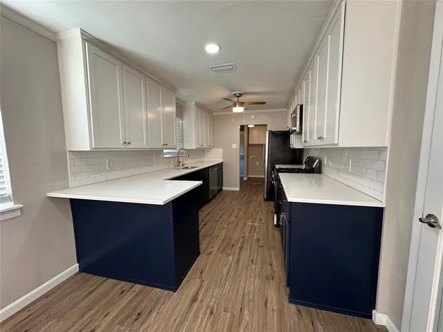 a kitchen with kitchen island wooden floors appliances and cabinets