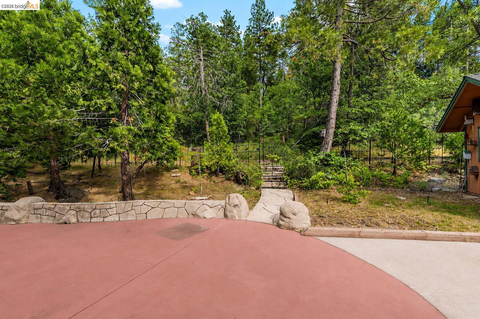 22401 Ridge Road Twain Harte, CA 95383 - Photo 36 of 56 Red-toned paved area featuring a stone retaining wall and mature trees