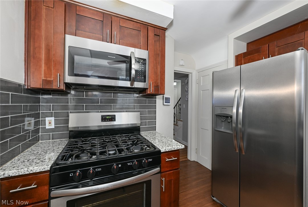 3699 Bainbridge Road Cleveland Heights, OH 44118 - Photo 13 of 37 Kitchen featuring wood-finish cabinetry, stainless steel microwave, stainless steel range, gray subway tile backsplash, and speckled countertops