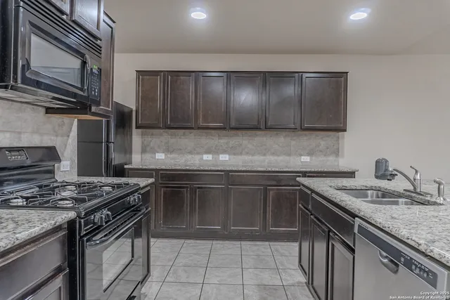 a kitchen with granite countertop a sink stove and cabinets