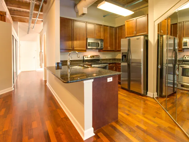 a kitchen with stainless steel appliances granite countertop a refrigerator a stove and a sink