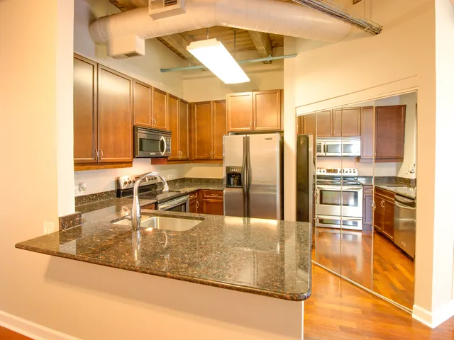 a kitchen with stainless steel appliances granite countertop a sink a stove and a refrigerator