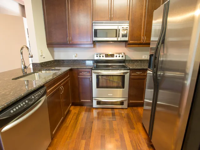 a kitchen with stainless steel appliances granite countertop a stove a sink and a refrigerator