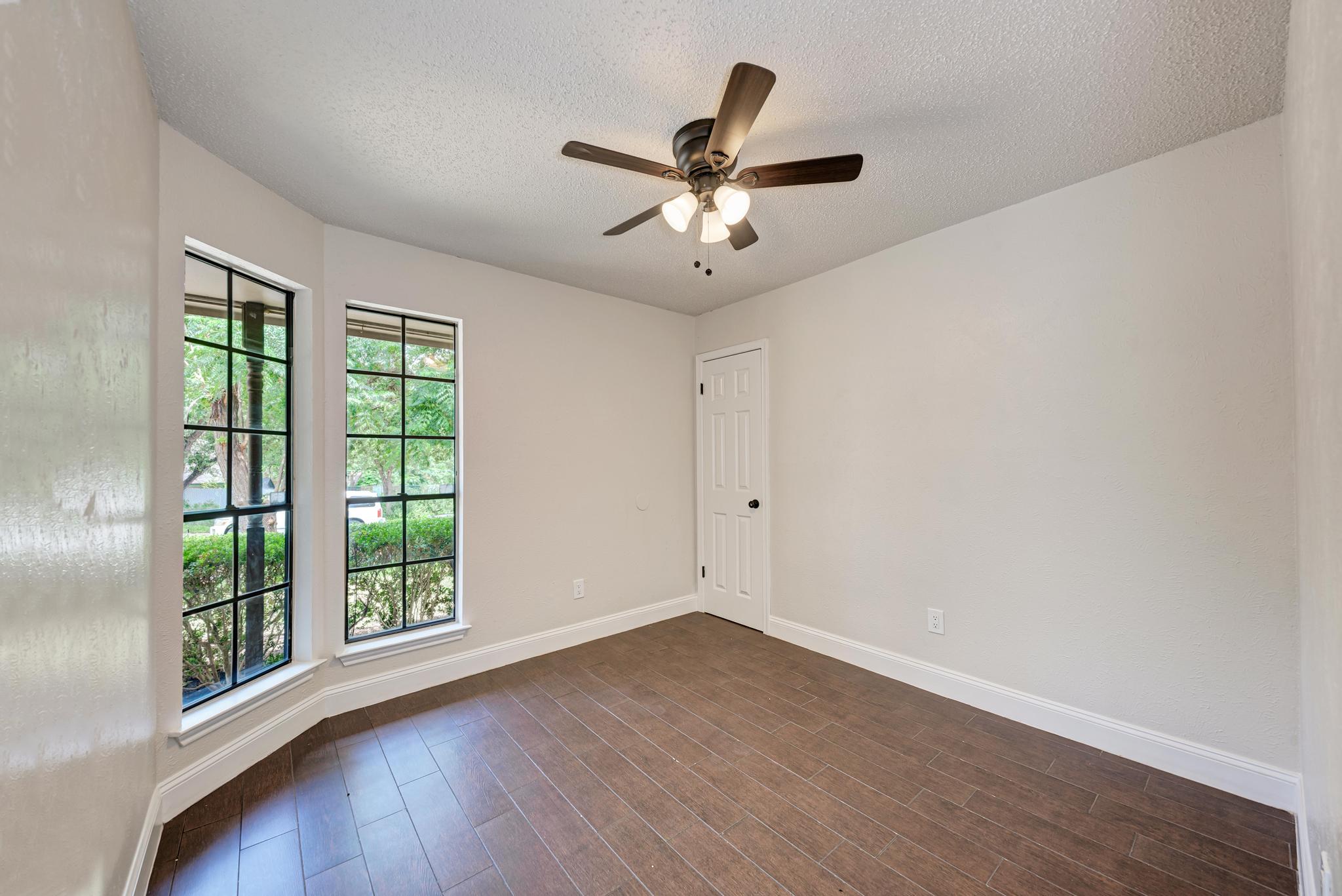 12108 Carnforth Drive Austin, TX 78753 - Photo 23 of 33 an empty room with wooden floor fan and windows